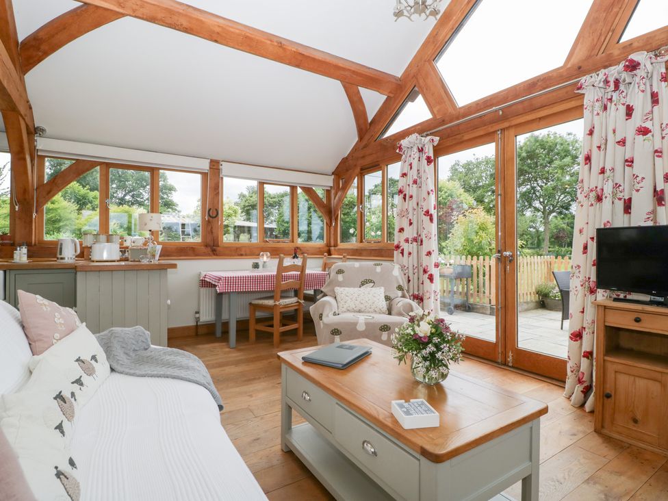 A living room with a sofa and dining table at Little Acorn Cottage in Munsley near Ledbury