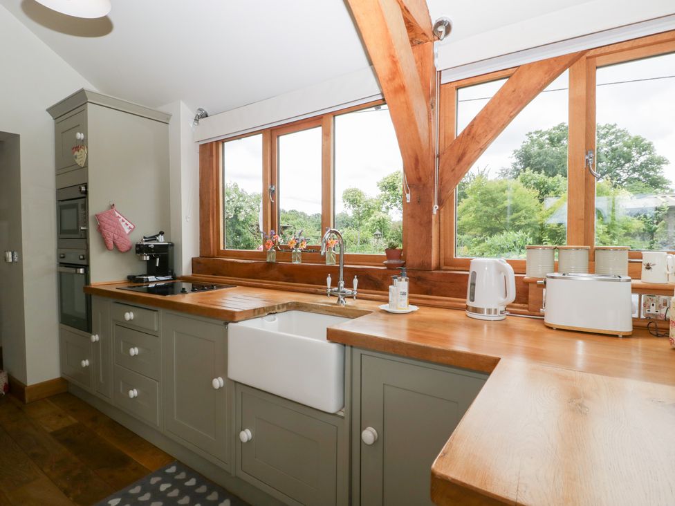 A kitchen with a sink and windows at Little Acorn Cottage in Munsley near Ledbury
