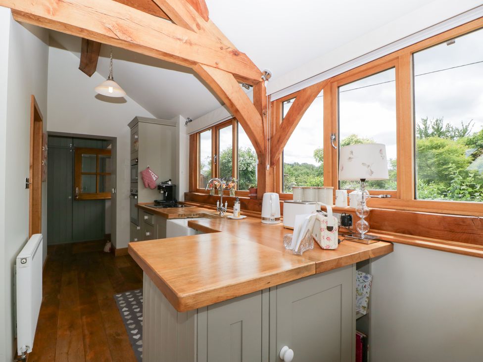 A kitchen with wooden beams and countertop at Little Acorn Cottage in Munsley near Ledbury