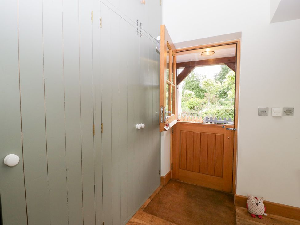 A hallway with wardrobe and door leading outside at Little Acorn Cottage in Munsley near Ledbury