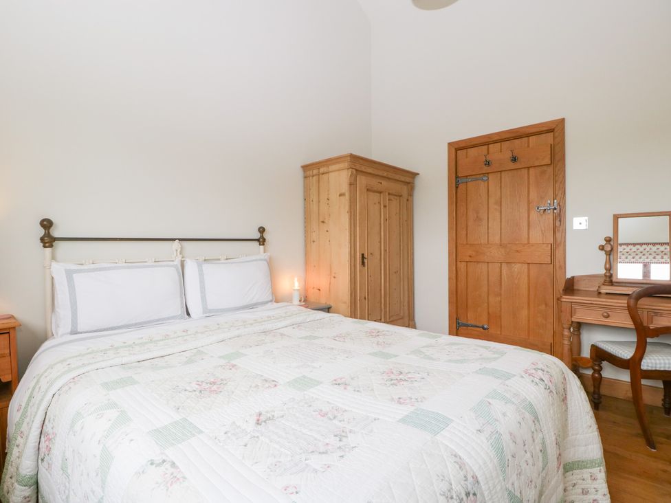 A bedroom with a bed and wardrobe at Little Acorn Cottage in Munsley near Ledbury
