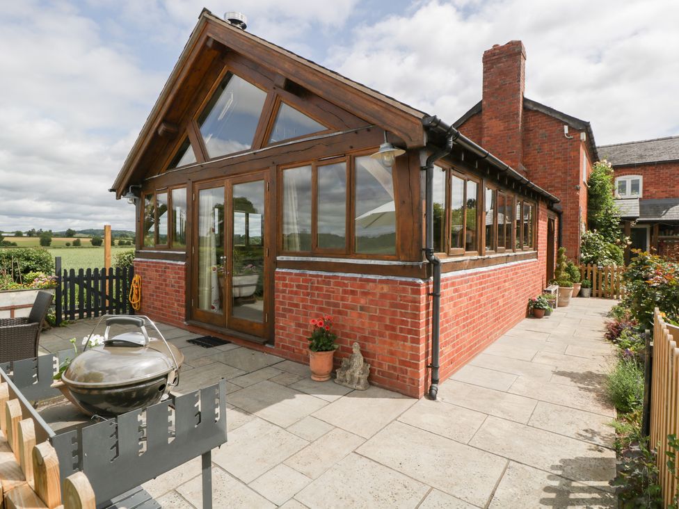 A conservatory with large windows and a barbecue at Little Acorn Cottage Munsley near Ledbury