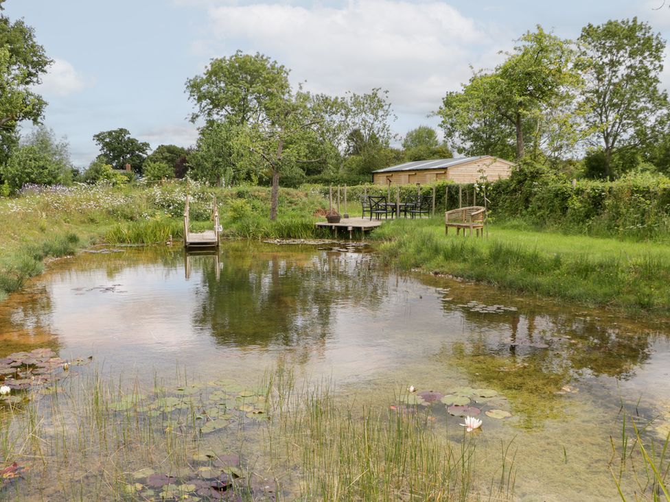 A garden with a pond and seating area at Little Acorn Cottage in Munsley near Ledbury