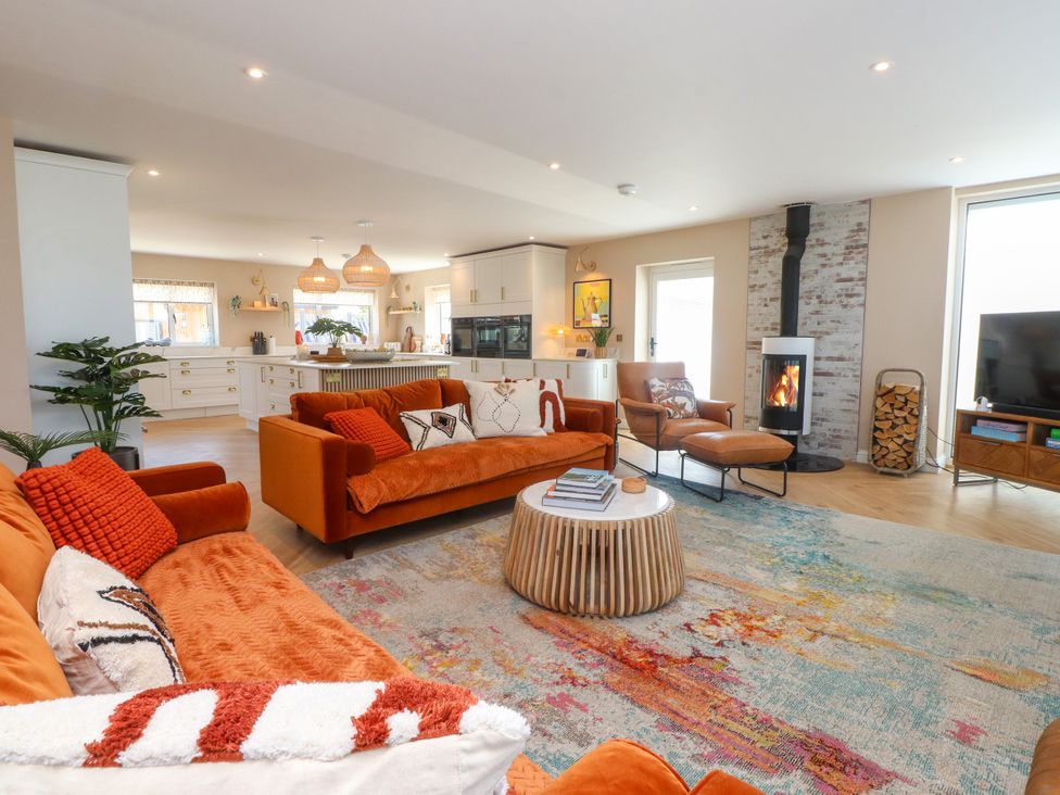 A living room with a sofa, fireplace, and television at Ardwyn, Rhosneigr