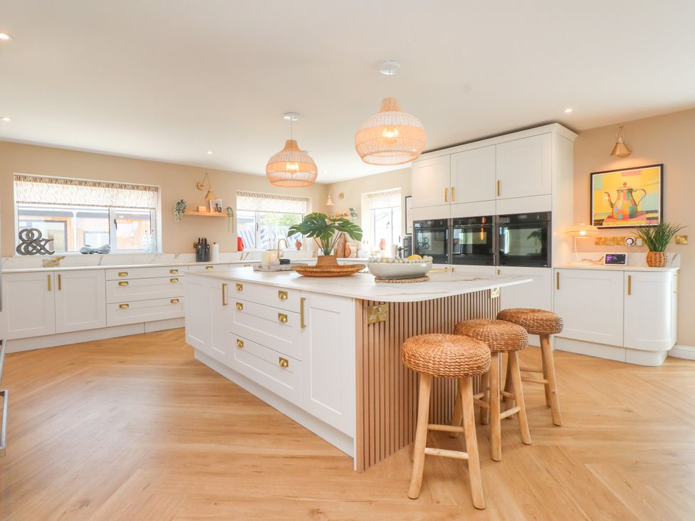 A kitchen with an island and stools at Ardwyn in Rhosneigr