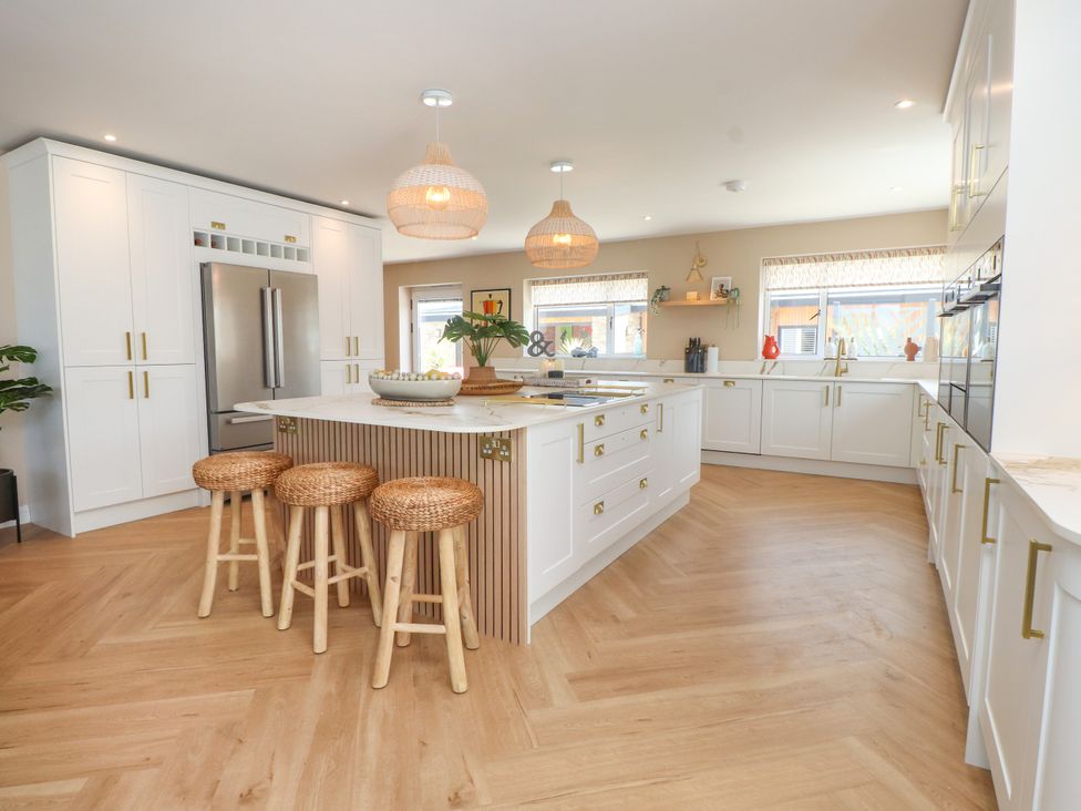 A kitchen with a central island and stools at Ardwyn Rhosneigr