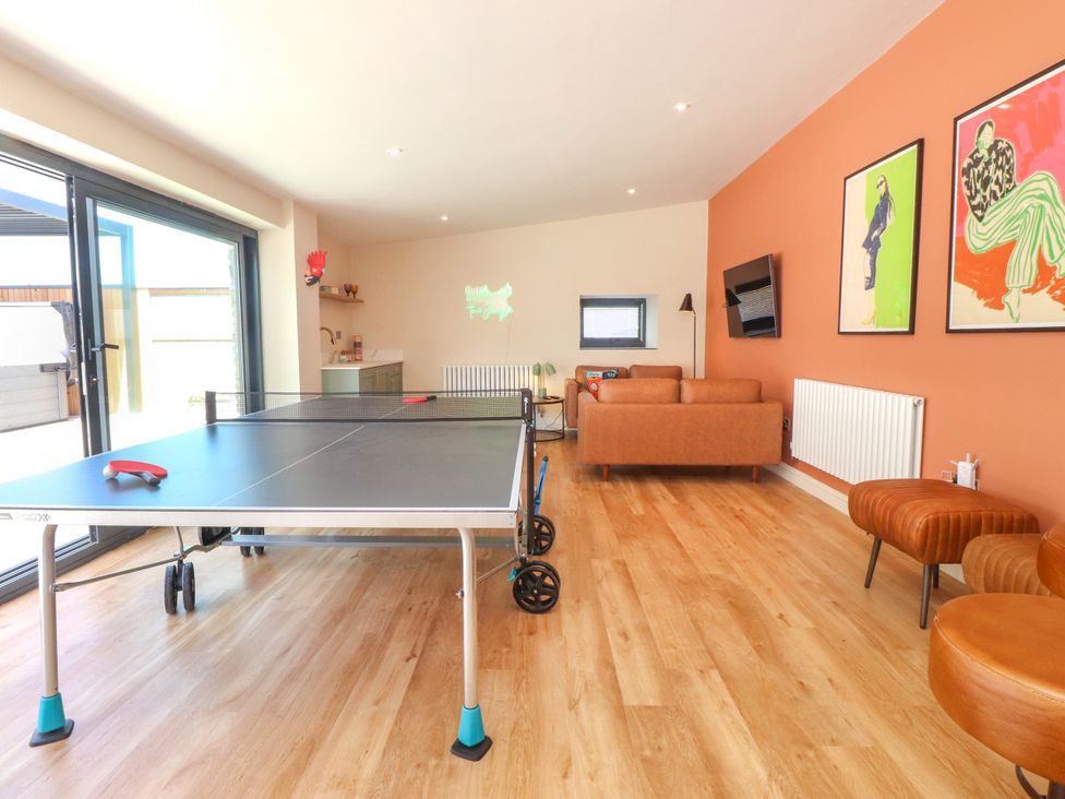 A game room with a table tennis table and sofa at Ardwyn Rhosneigr