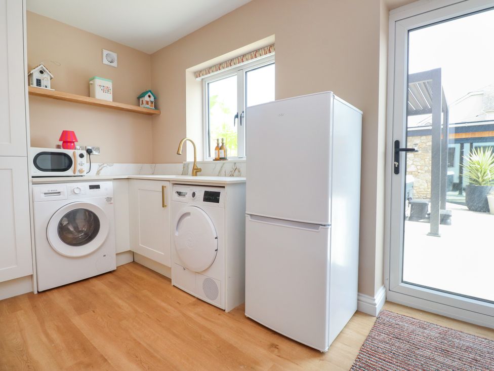 A laundry room with appliances and window at Ardwyn Rhosneigr