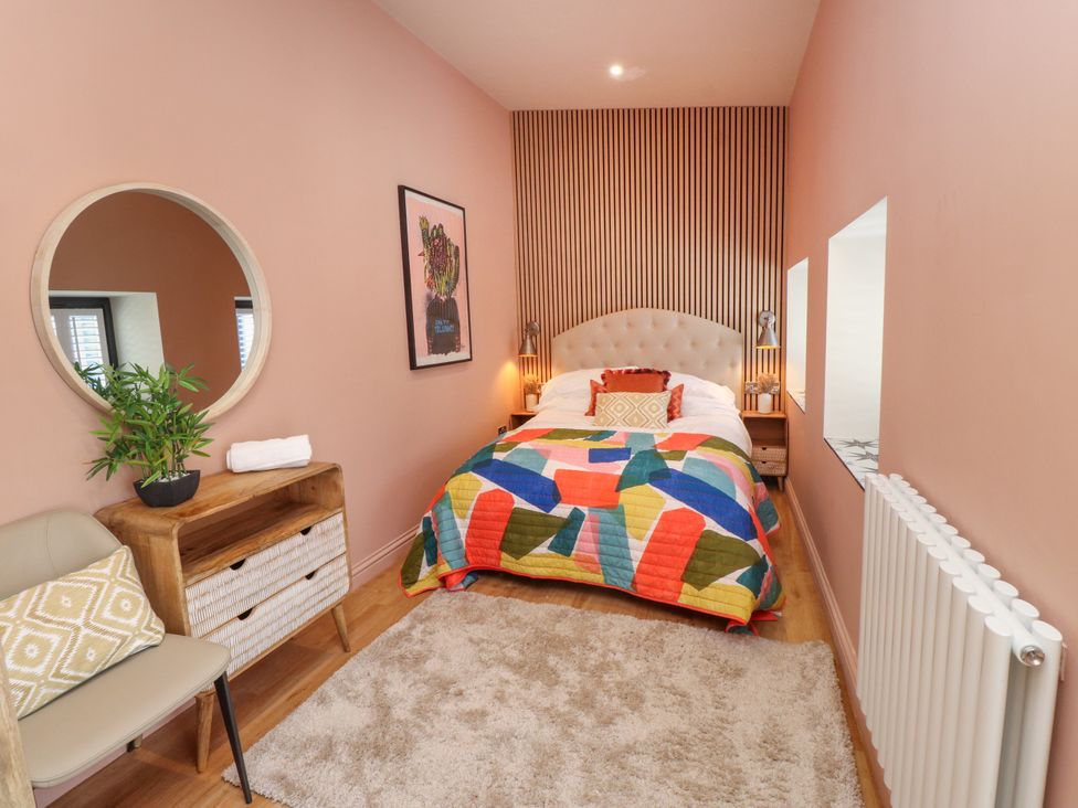 A bedroom with a bed and colorful quilt at Ardwyn in Rhosneigr
