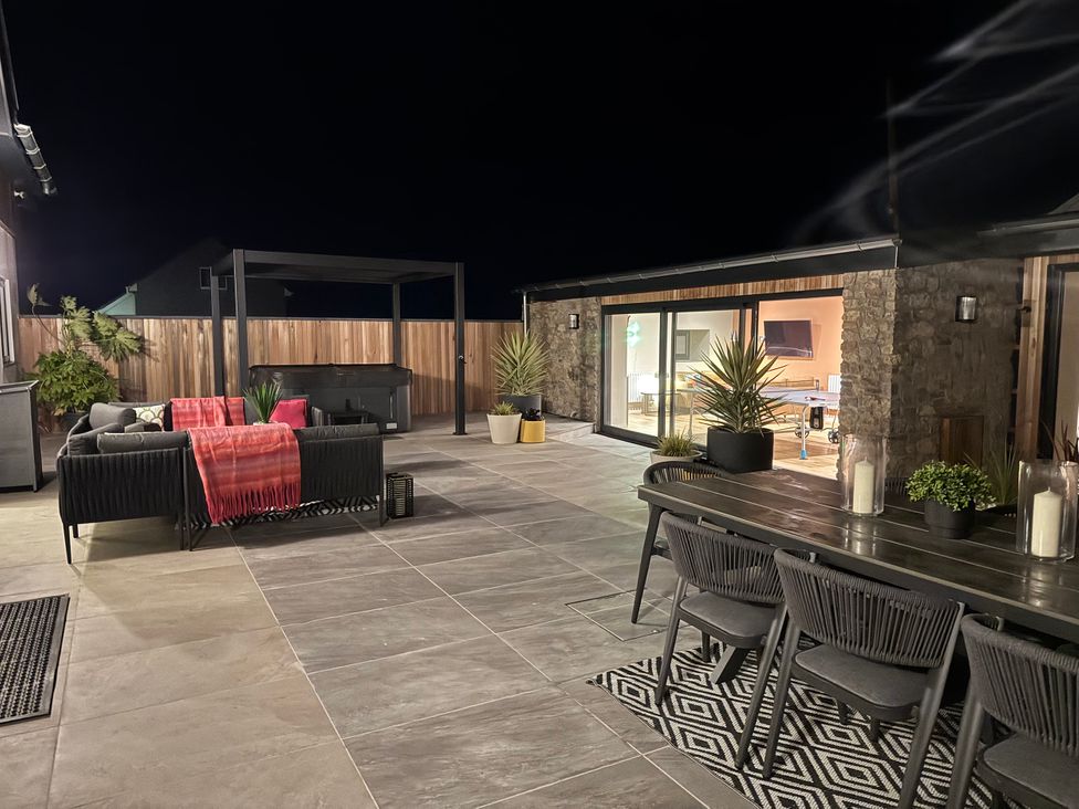 An outdoor area with a hot tub, seating and dining table at Ardwyn Rhosneigr