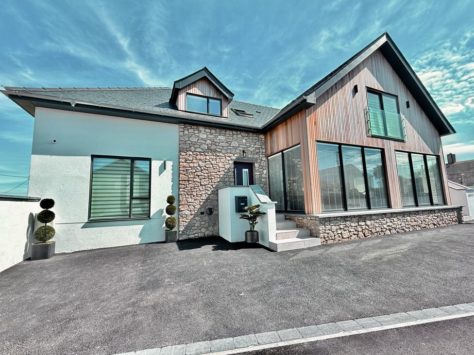 A house with stone wall and large windows at Ardwyn Rhosneigr