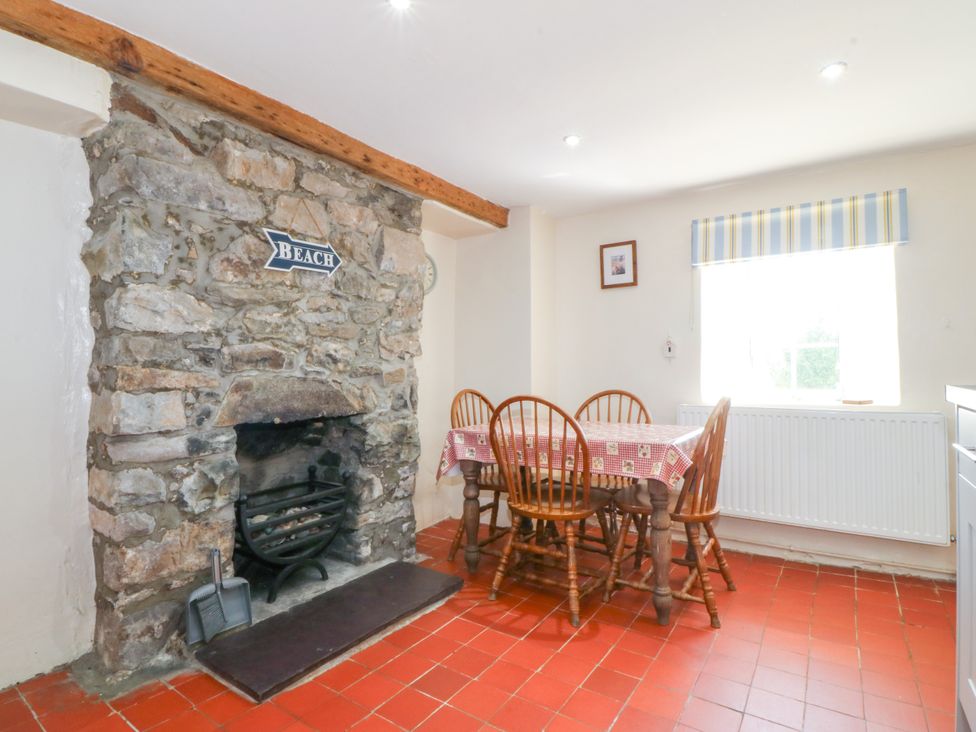 A dining room with a stone fireplace and wooden table at Brynffynon in Pwllheli