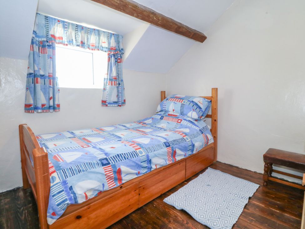 A bedroom with a bed, window, and chair at Brynffynon in Pwllheli