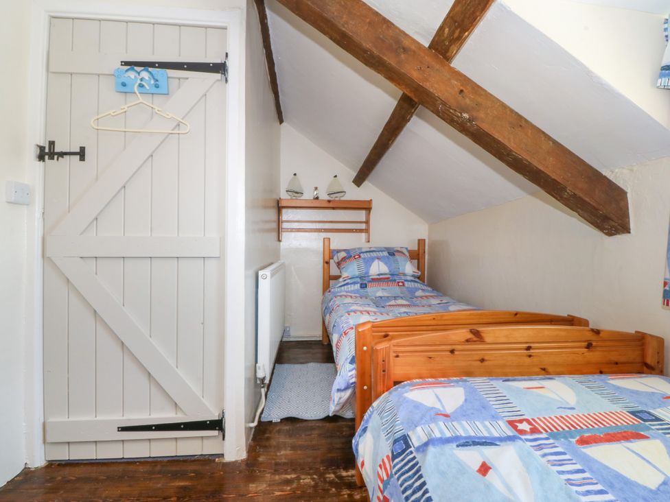 A bedroom with two beds and a shelf at Brynffynon in Pwllheli