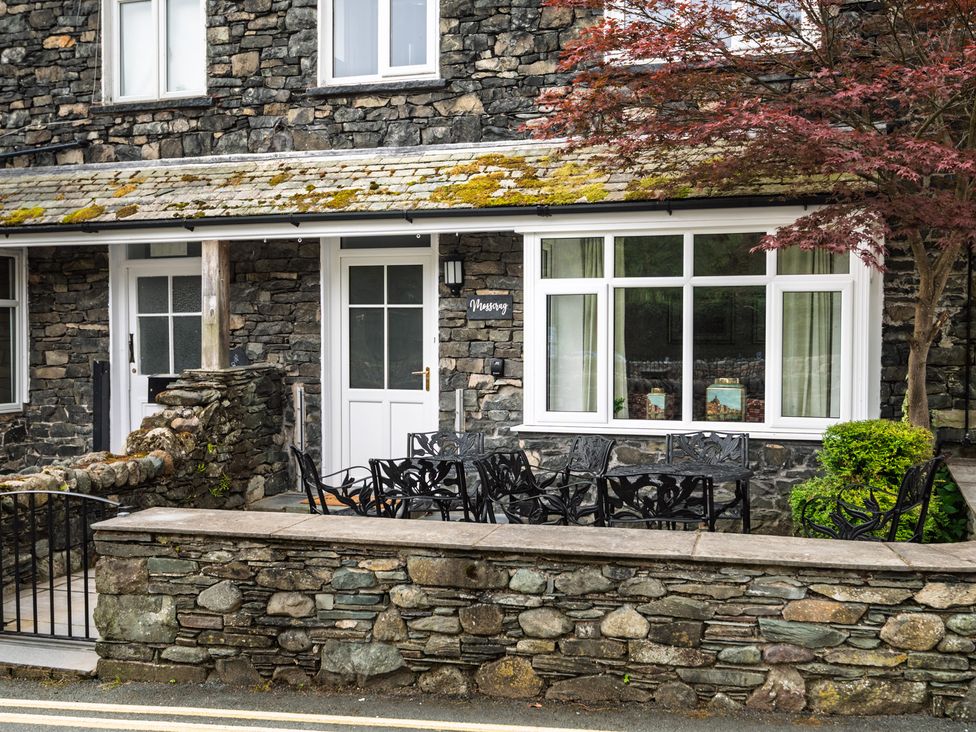 An outdoor seating area with a stone wall and chairs at Moss Crag in Glenridding