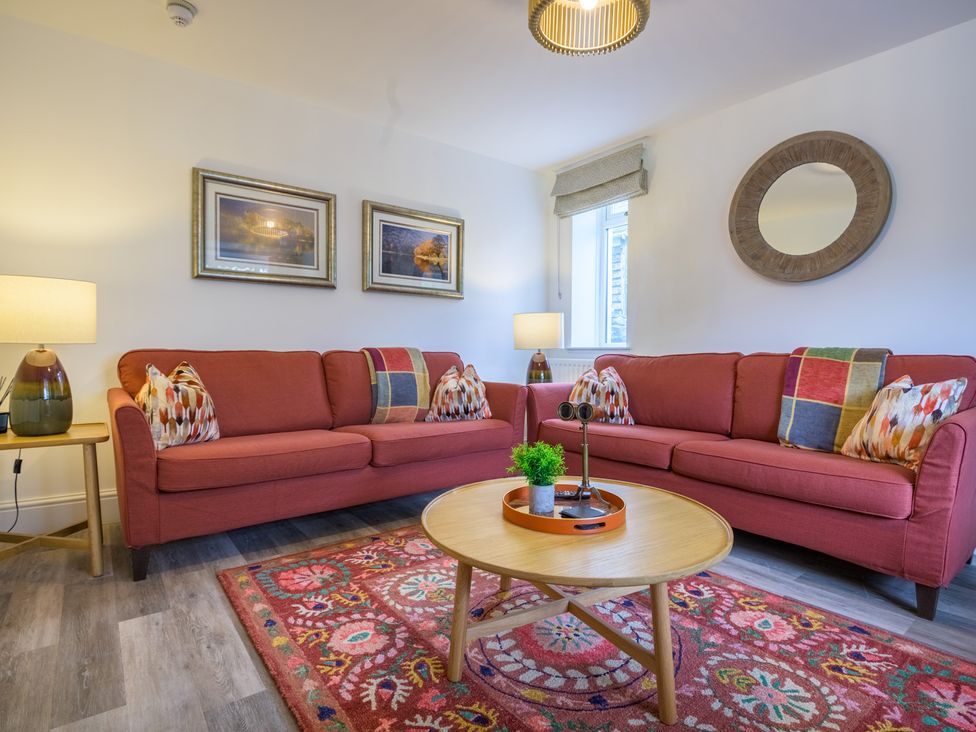 A living room with a sofa, coffee table, and lamp at Moss Crag in Glenridding
