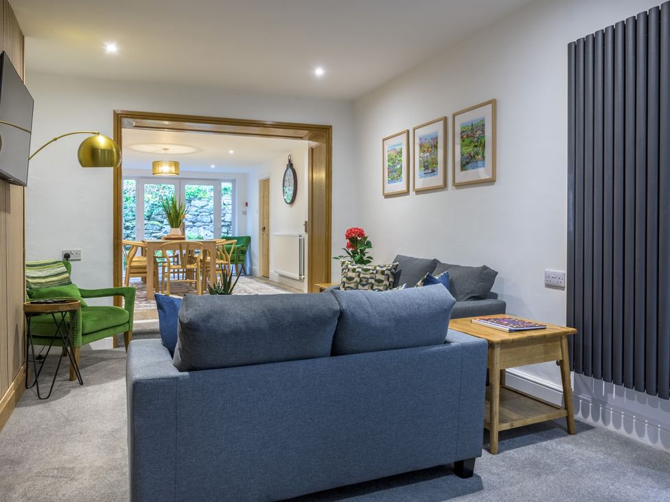 A living room with a sofa, armchair, and dining area at Moss Crag in Glenridding