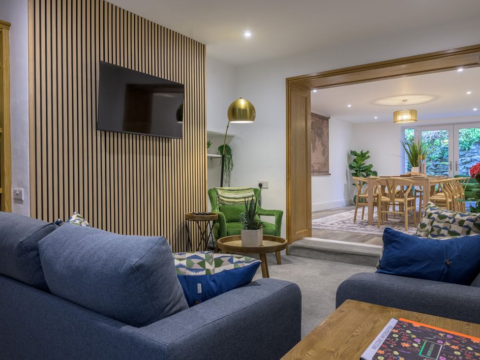 A living room with a sofa and television leading to dining area at Moss Crag in Glenridding