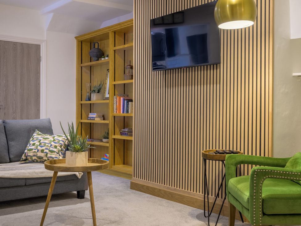 A living room with a sofa and bookshelf at Moss Crag in Glenridding