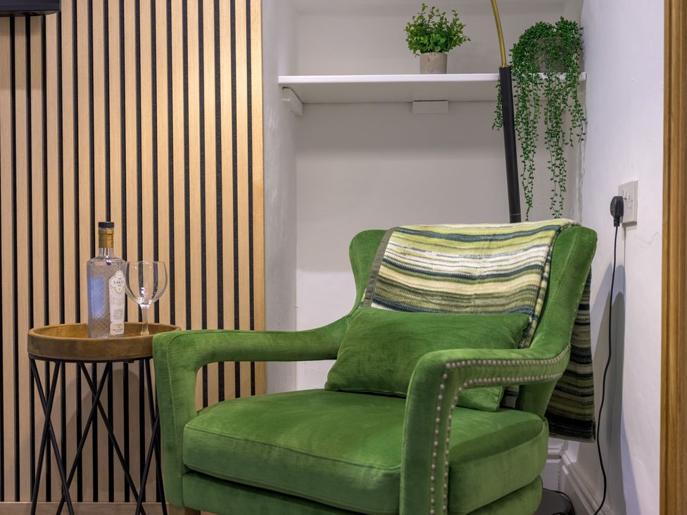 A living room with a green chair and a side table at Moss Crag in Glenridding