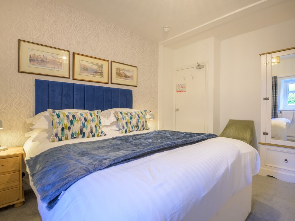 A bedroom with a blue headboard and framed pictures at Moss Crag in Glenridding