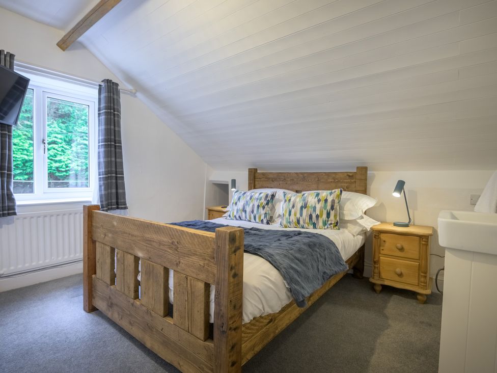 A bedroom with a wooden bed and nightstand at Moss Crag in Glenridding