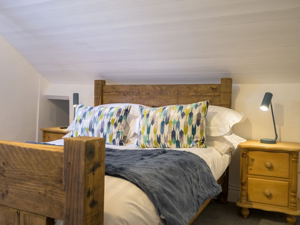 A bedroom with a wooden bed and bedside table at Moss Crag in Glenridding
