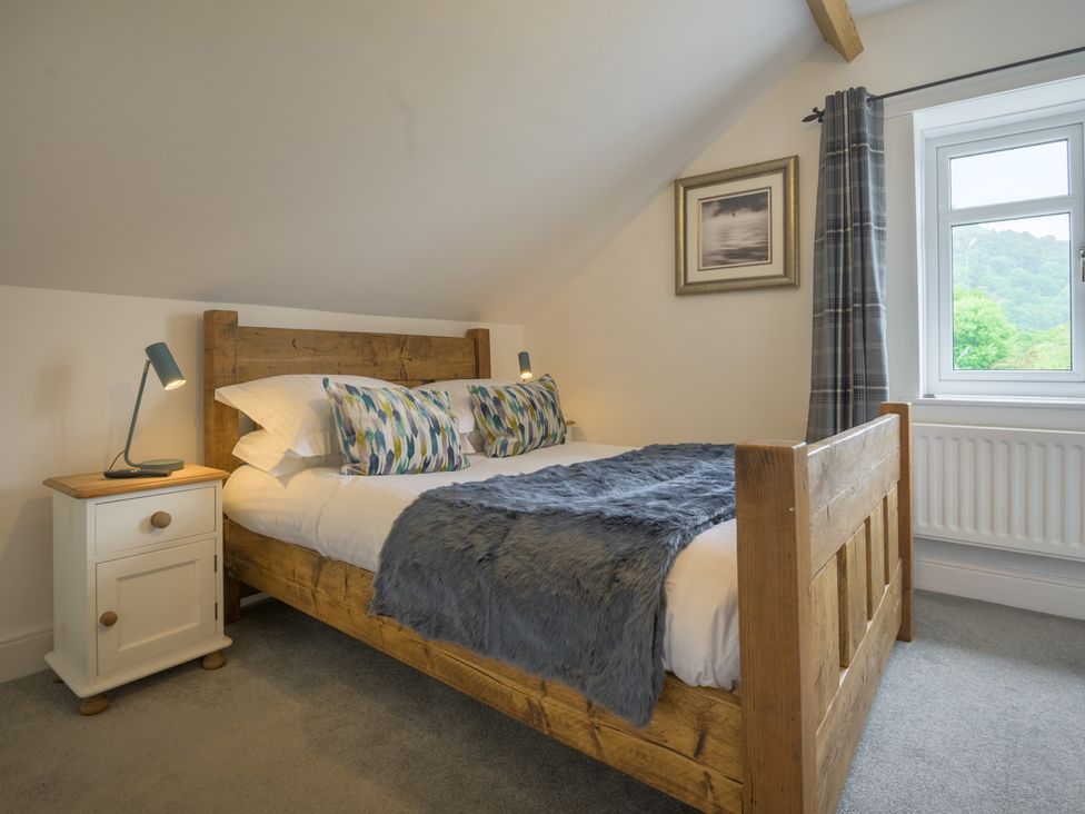 A bedroom with a wooden bed and a lamp at Moss Crag in Glenridding