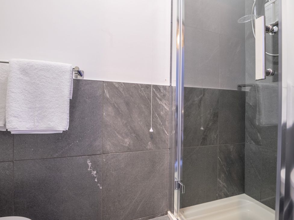 A bathroom with a shower and towels hanging at Moss Crag in Glenridding