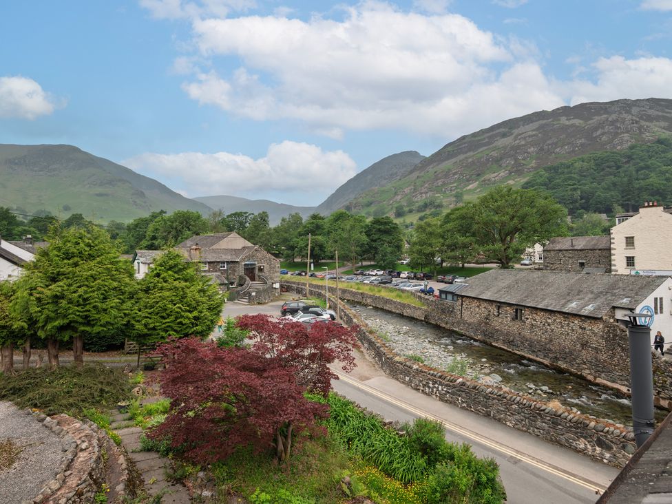 A view of buildings and a stream with trees at Moss Crag in Glenridding