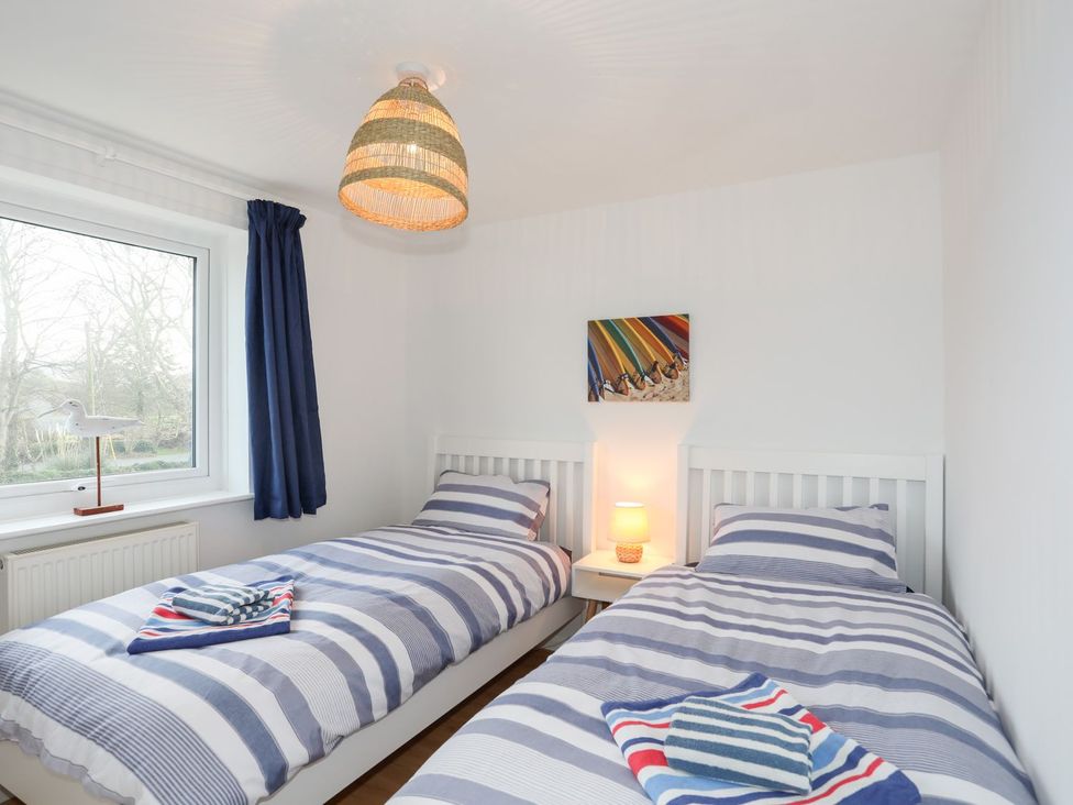 A bedroom with two single beds and a lamp at 15 Llwyn Gwalch Estate Pwllheli