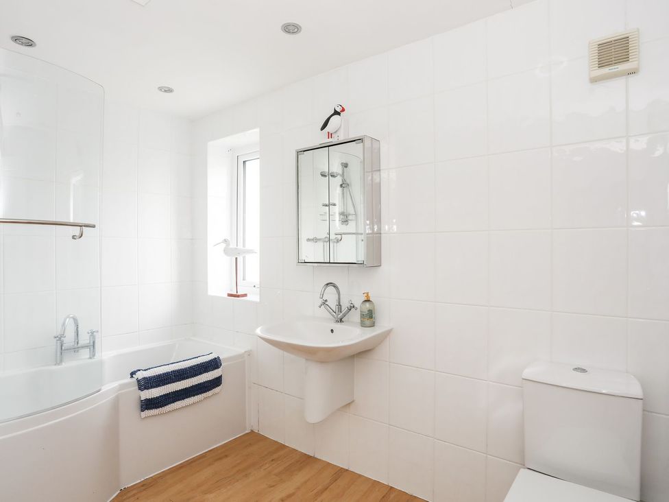 A bathroom with a bathtub, wash basin, and toilet at 15 Llwyn Gwalch Estate Pwllheli