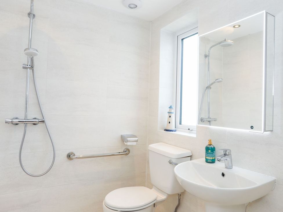 A bathroom with a shower, toilet, and sink at 15 Llwyn Gwalch Estate in Pwllheli