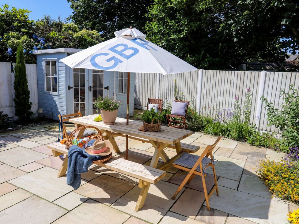 A garden with a table and umbrella at 15 Llwyn Gwalch Estate, Pwllheli