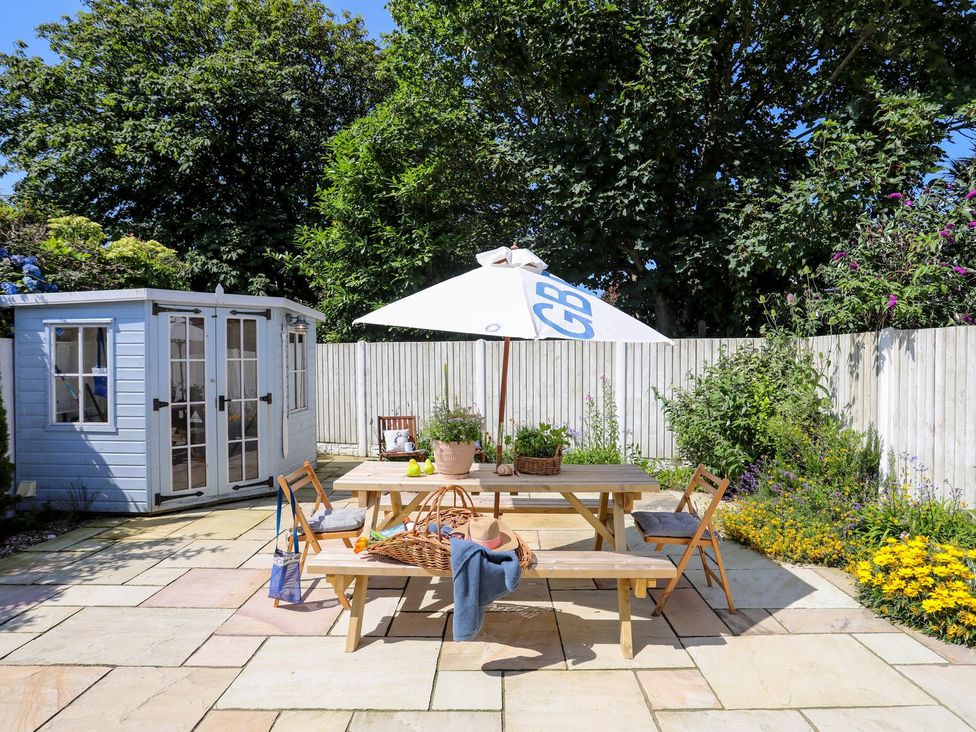 A garden with table and chairs under an umbrella at 15 Llwyn Gwalch Estate Pwllheli