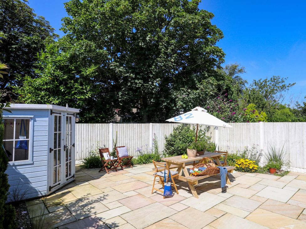 A garden with a table and umbrella at 15 Llwyn Gwalch Estate Pwllheli