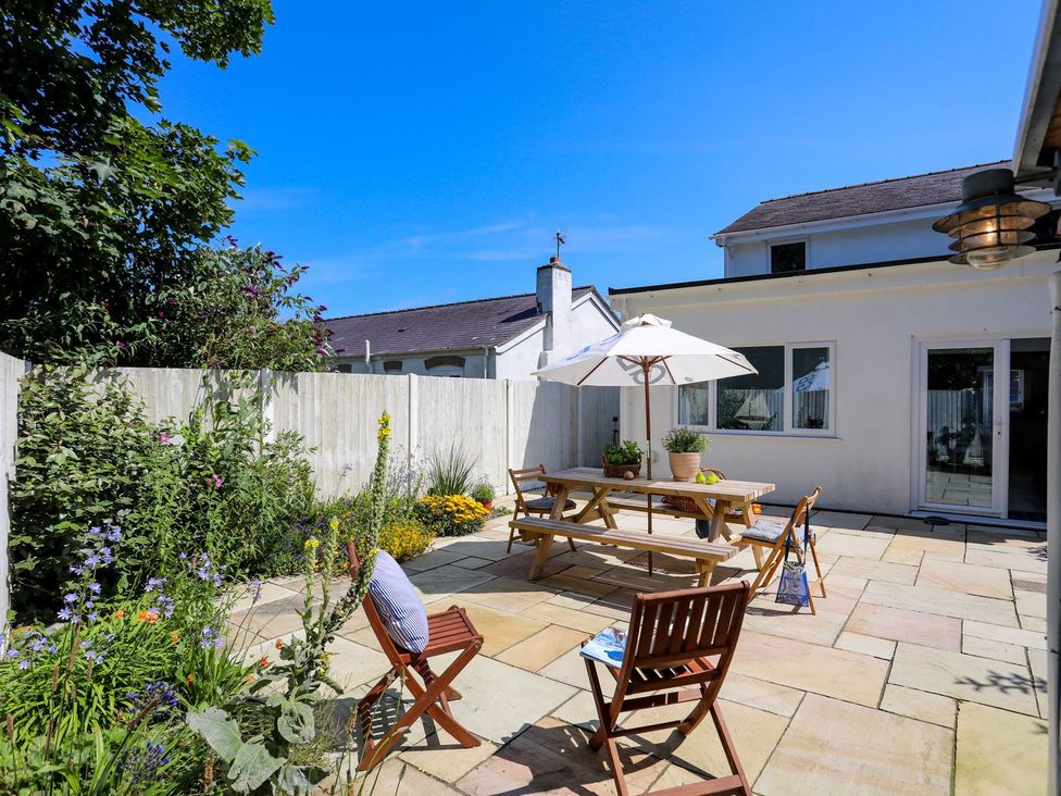 A garden with a table and chairs under an umbrella at 15 Llwyn Gwalch Estate Pwllheli