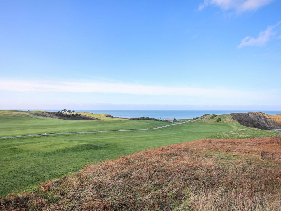 A landscape with grass and hills leading to the sea at 15 Llwyn Gwalch Estate Pwllheli