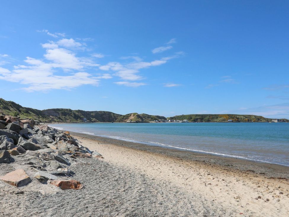 A beach with rocks and water at 15 Llwyn Gwalch Estate Pwllheli