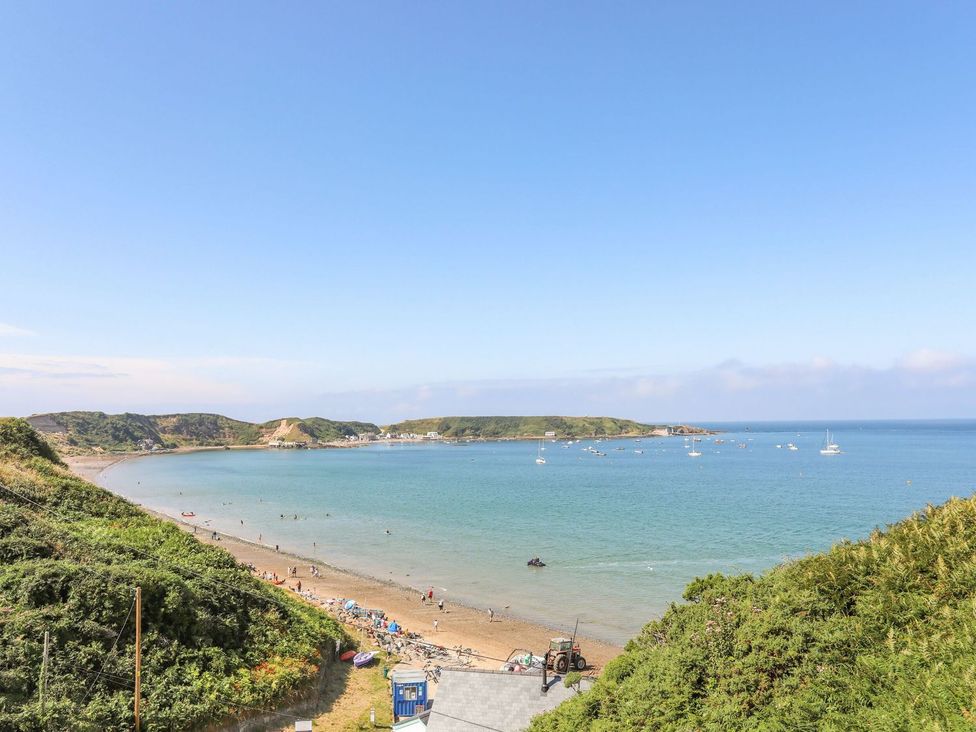 A beach with water and boats at 15 Llwyn Gwalch Estate in Pwllheli