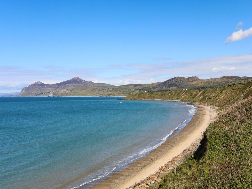 A beach with mountains in the background at 15 Llwyn Gwalch Estate Pwllheli