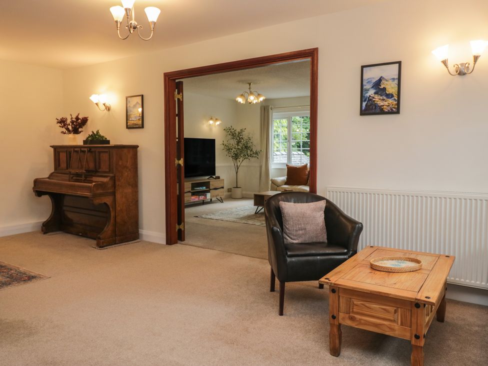 A living room with a piano and armchair at Cumbria house 
