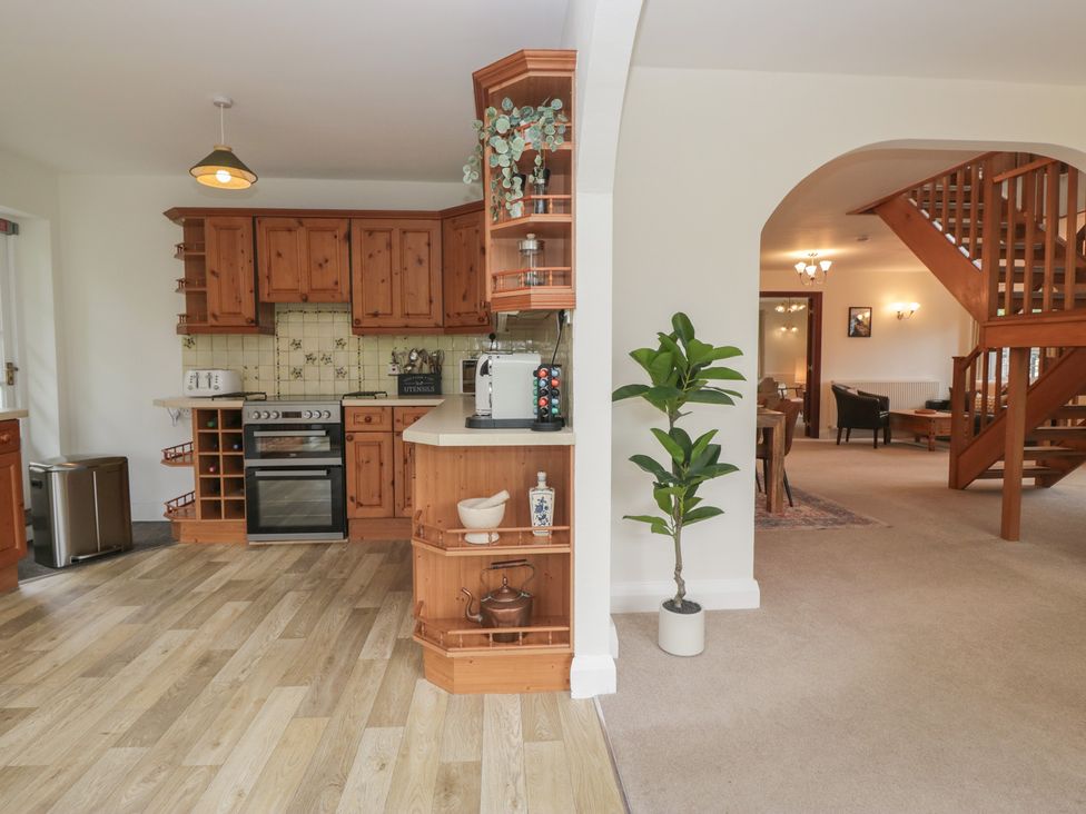 A kitchen with wooden cabinets and a dining area at Cumbria house
