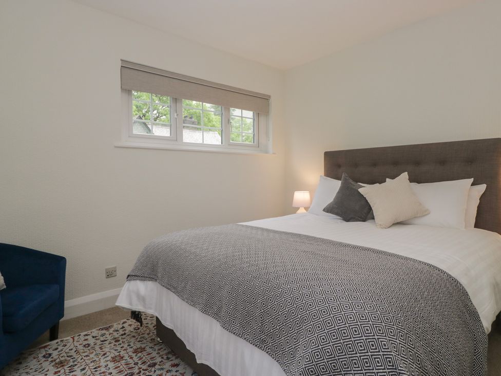 A bedroom with a bed, lamp, window, and chair at Cumbria house