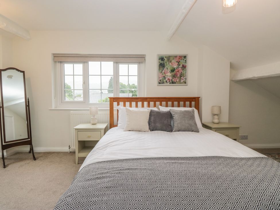 A bedroom with a bed, nightstands and a mirror at Cumbria house