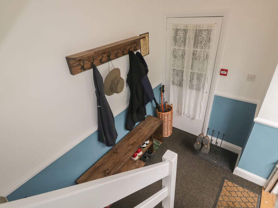 A hallway with coat rack, bench, and shoes at Cumbria house