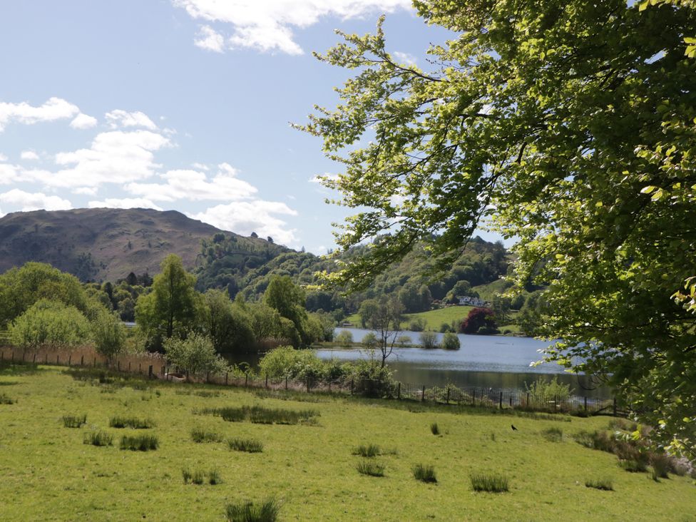 A landscape view of a lake surrounded by trees and hills at Cumbria house