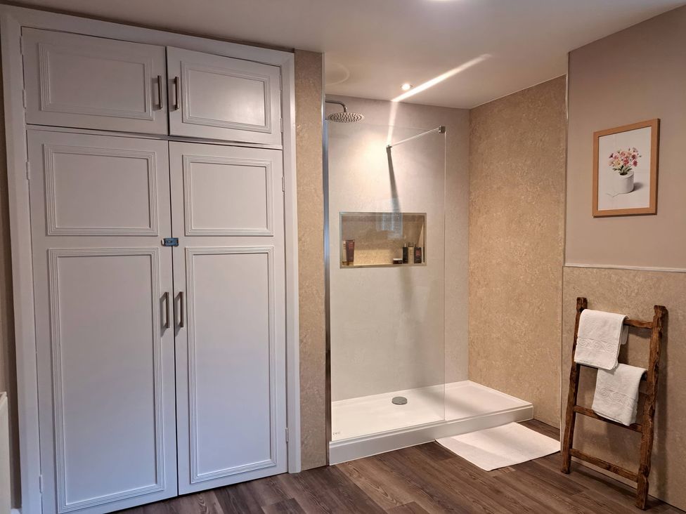 A bathroom with a shower and towels on a rack at Cumbria house in Grasmere