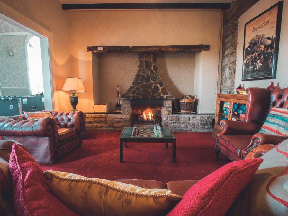 A living room with a fireplace and chairs at Noddfa Country House in Harlech