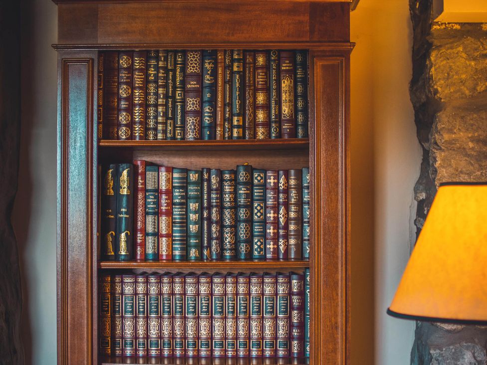 A bookshelf filled with books and a lamp in the library at Noddfa Country House Harlech